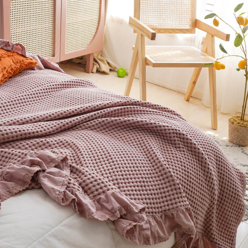 Detail of the ruffled edge and high-quality cotton fabric of a rose pink waffle blanket.