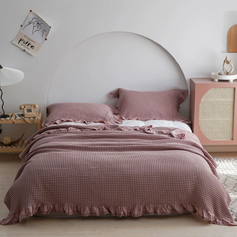 Dusty rose pink cotton waffle blanket and matching pillowcases with ruffle details.