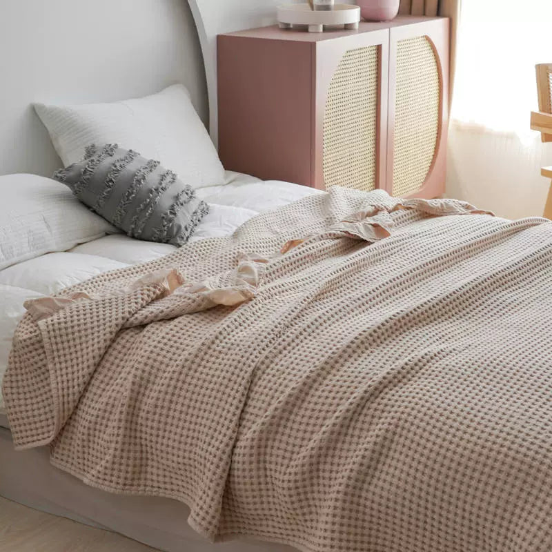 Close-up of beige breathable woven texture waffle blanket with decorative ruffles.