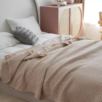 Close-up of beige breathable woven texture waffle blanket with decorative ruffles.