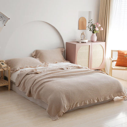 Beige cotton waffle blanket set including ruffled pillows in a modern minimalist interior.