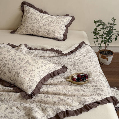 Brown floral comforter with mocha ruffled lace trim styled in a warm vintage bedroom