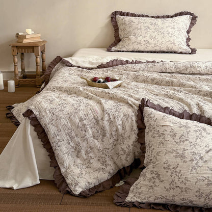 Brown floral cotton comforter layered with matching pillows and mocha lace edging