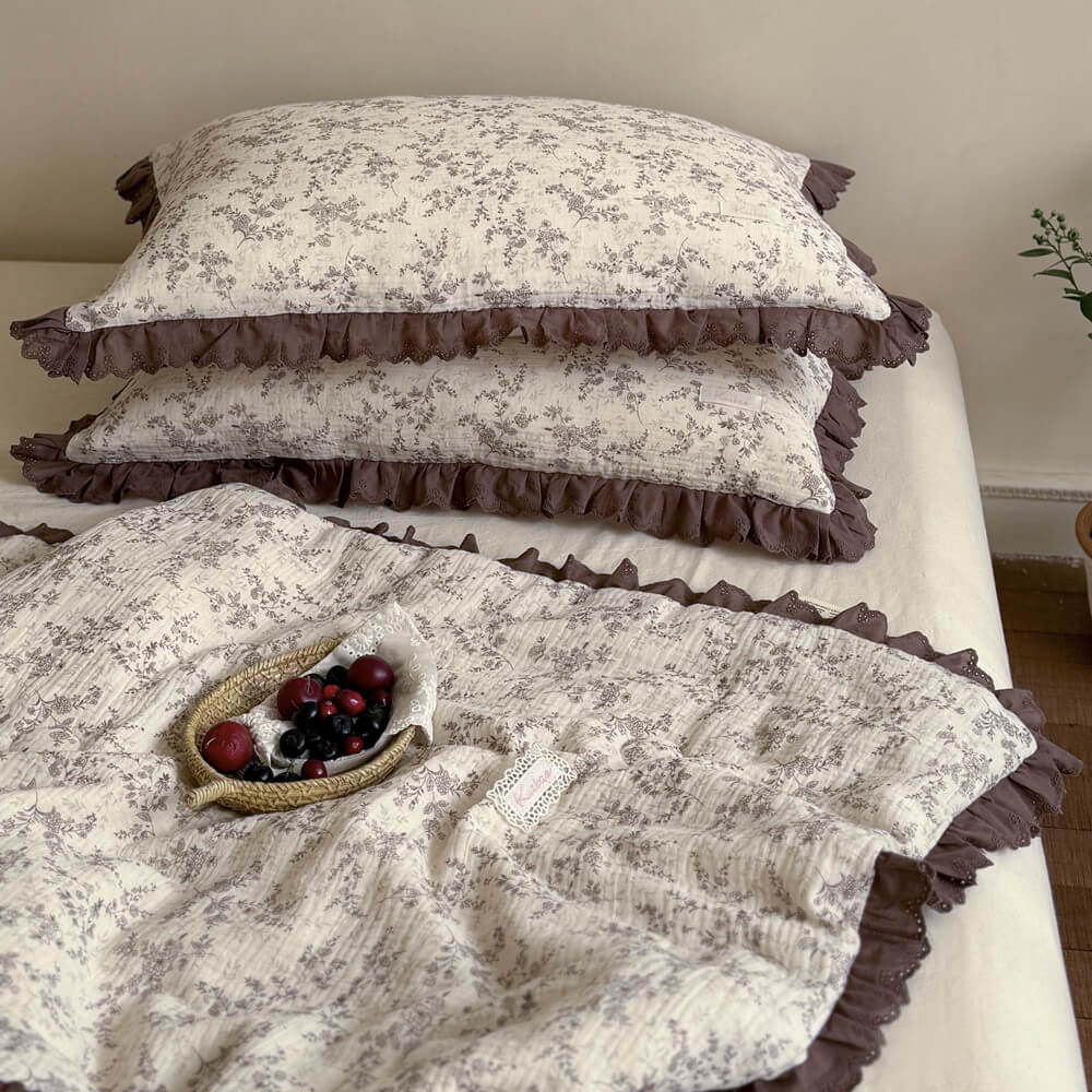Folded brown floral cotton comforter with layered mocha ruffled lace trim on a neutral bed