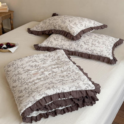Folded brown floral comforter showing soft crinkled fabric and layered mocha lace trim