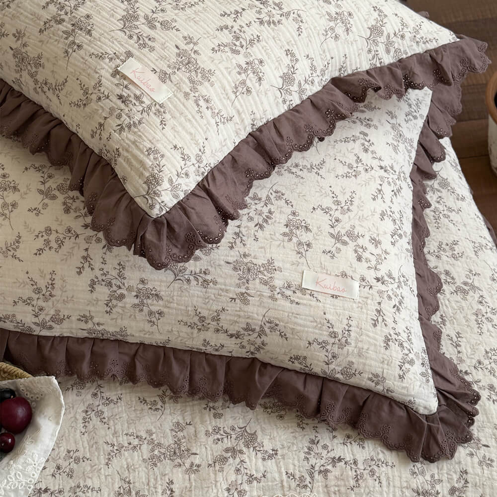 Close-up of brown floral comforter and matching pillow with deep mocha ruffled lace details