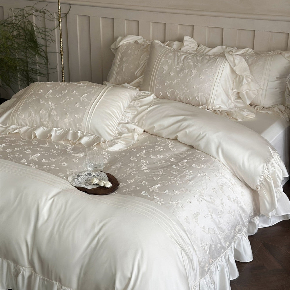 Ivory butterfly embroidered bedding set on a bed with matching pillowcase.