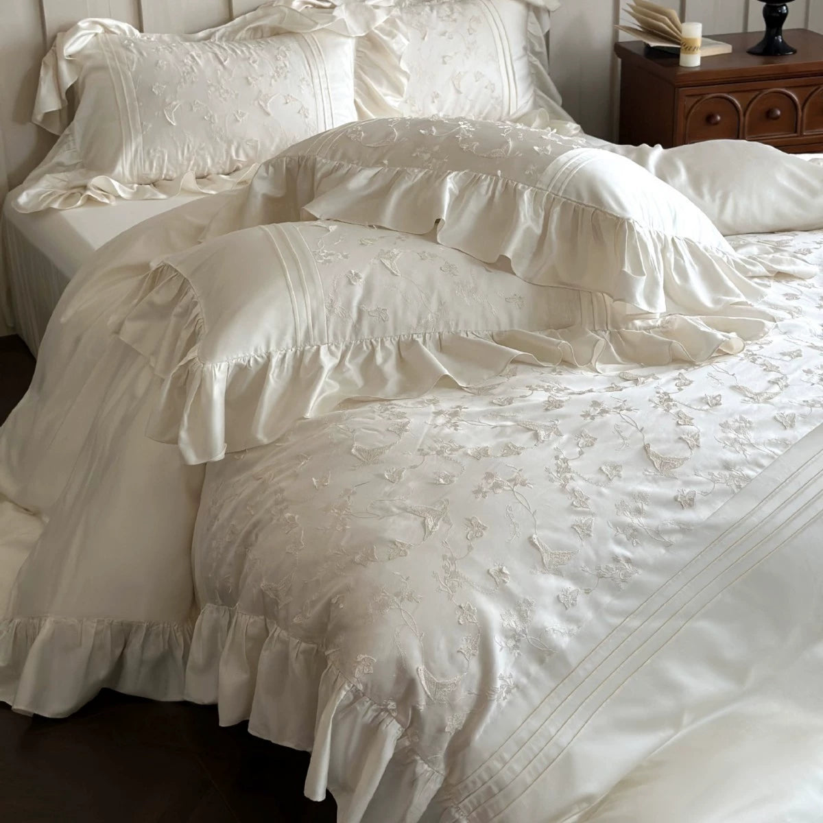White textured bedding set on a bed with a wooden nightstand in the background.