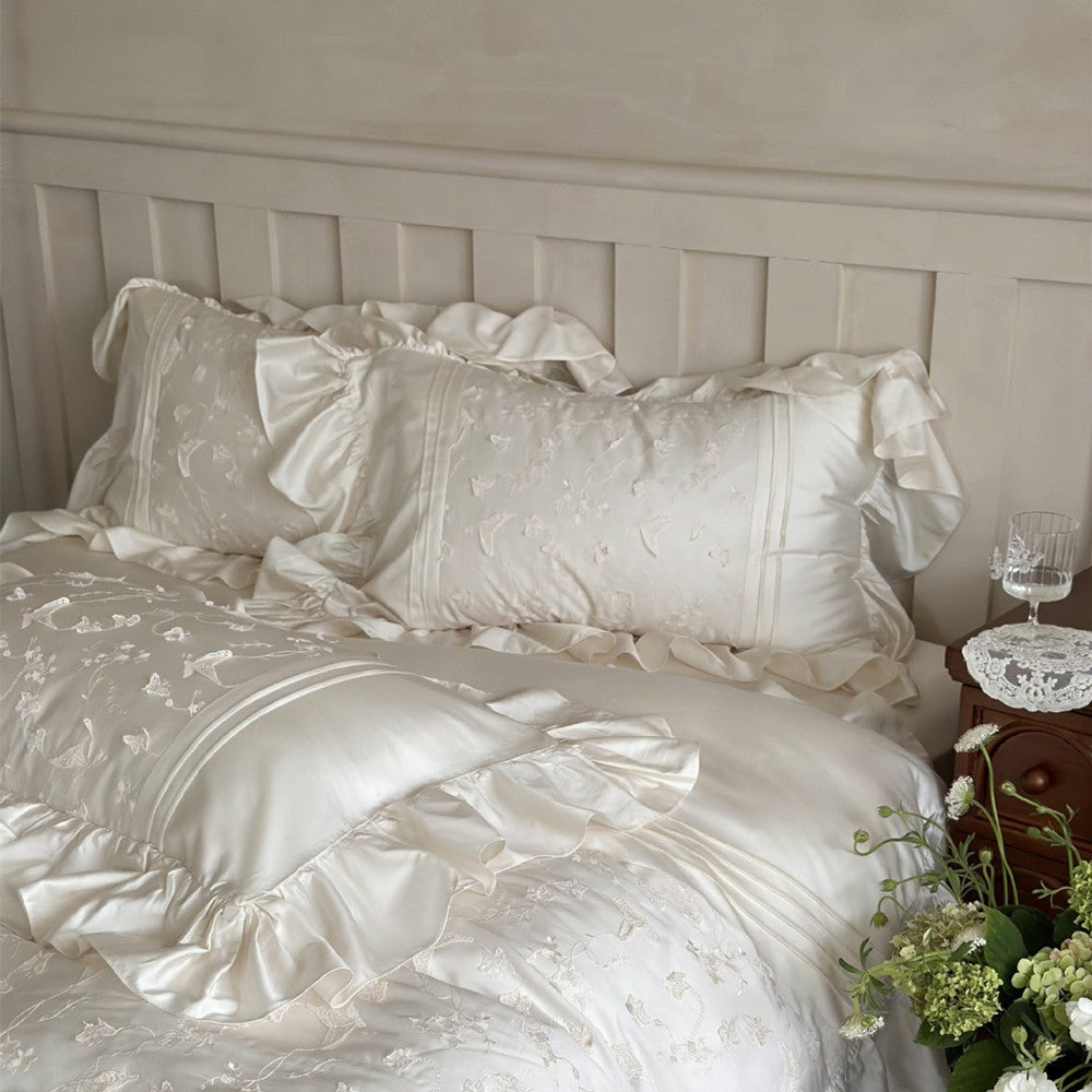 White bedding set with ruffles on a bed in a bedroom setting.