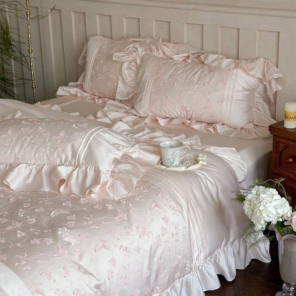 Styled image of the pink Butterfly Embroidered Bedding Set with multiple ruffled pillows and a tray.