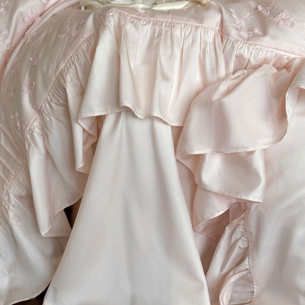  Detail shot of the gathered ruffles and silky fabric texture of the pink bedding set.