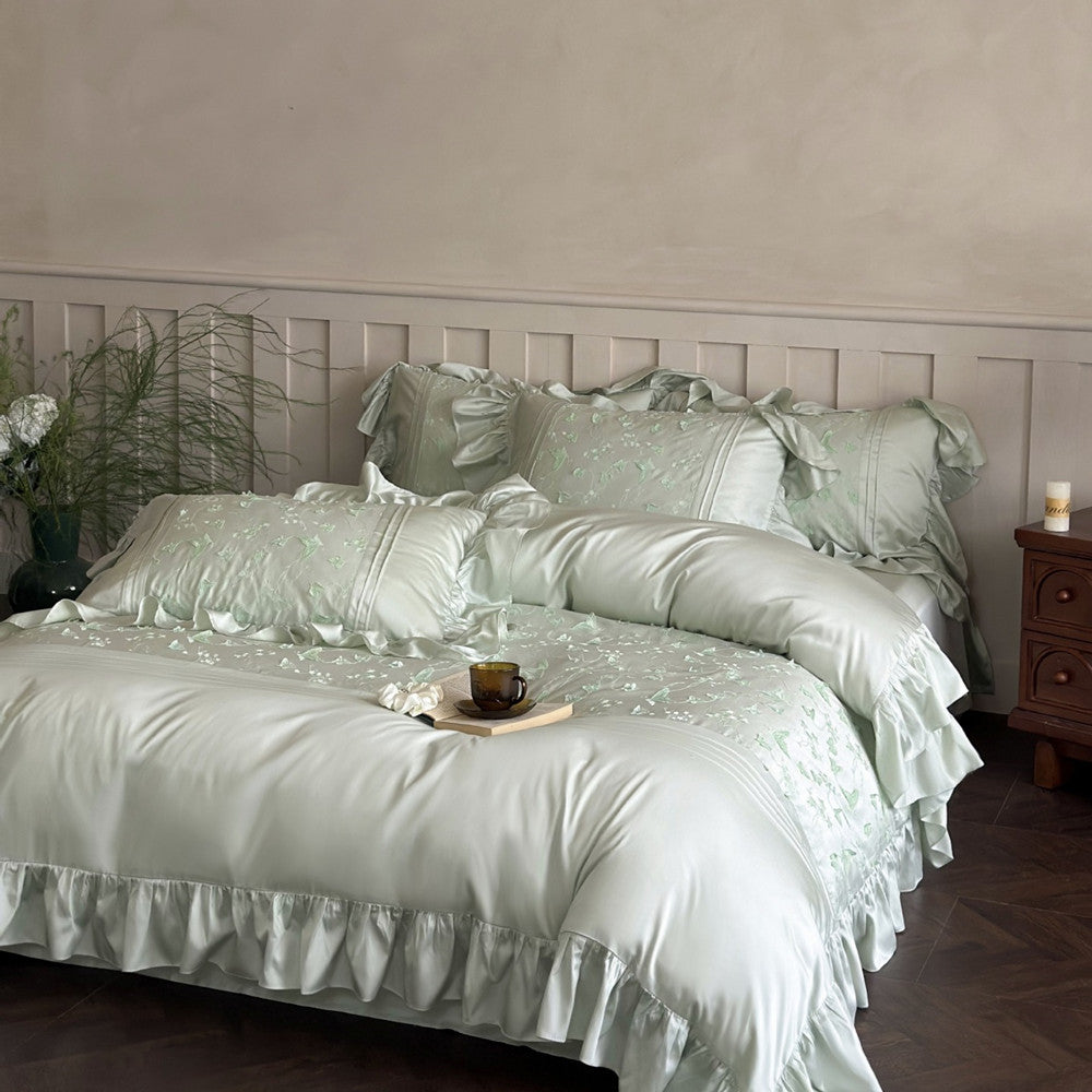 Light green Butterfly Embroidered Bedding Set with ruffles styled on a bed in an elegant room.