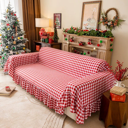 Living room with red buffalo plaid sofa cover featuring ruffles, decorated for Christmas with tree and festive mantel
