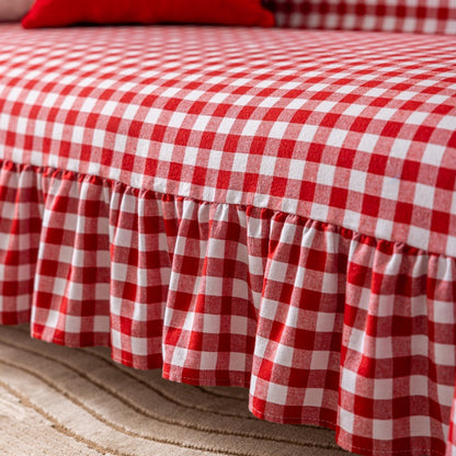 Red and white buffalo plaid sofa cover with ruffled skirt on beige carpet, cozy home decor