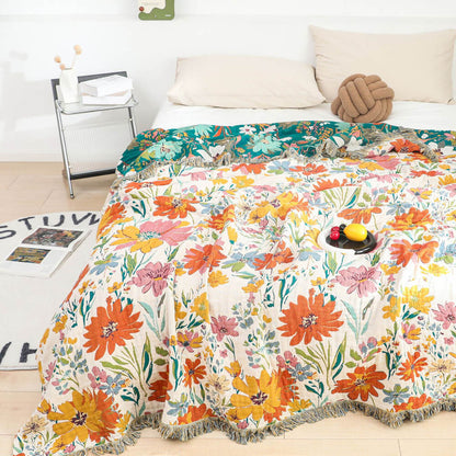 Reversible floral cotton throw blanket showing ivory floral side and deep green floral underside on a bed