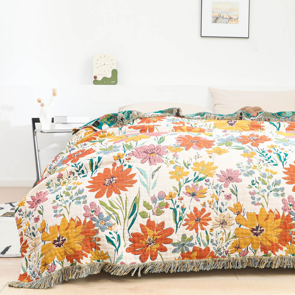 Colorful floral cotton throw blanket with fringe spread across a white bed