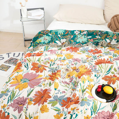 Close view of colorful floral cotton throw blanket with fringe layered over a bed