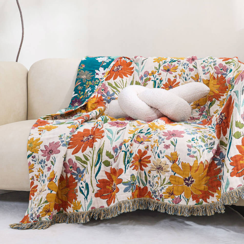 Colorful floral cotton throw blanket with fringe draped over a cream sofa