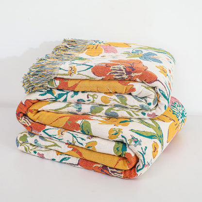 Folded colorful floral cotton throw blanket showing woven texture and multicolor fringe
