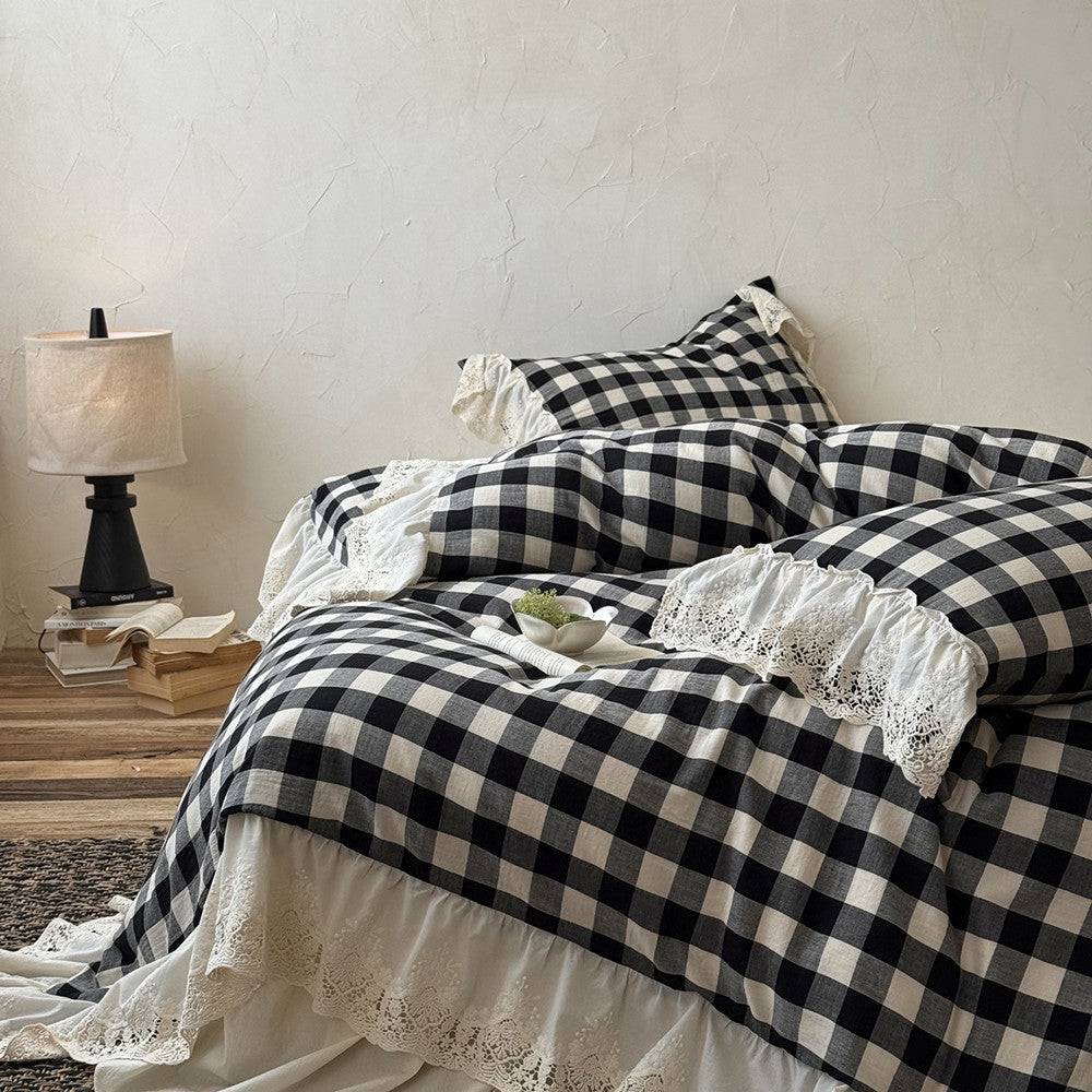 Black and white checkered bedspread with lace details on a bed in a bedroom setting.