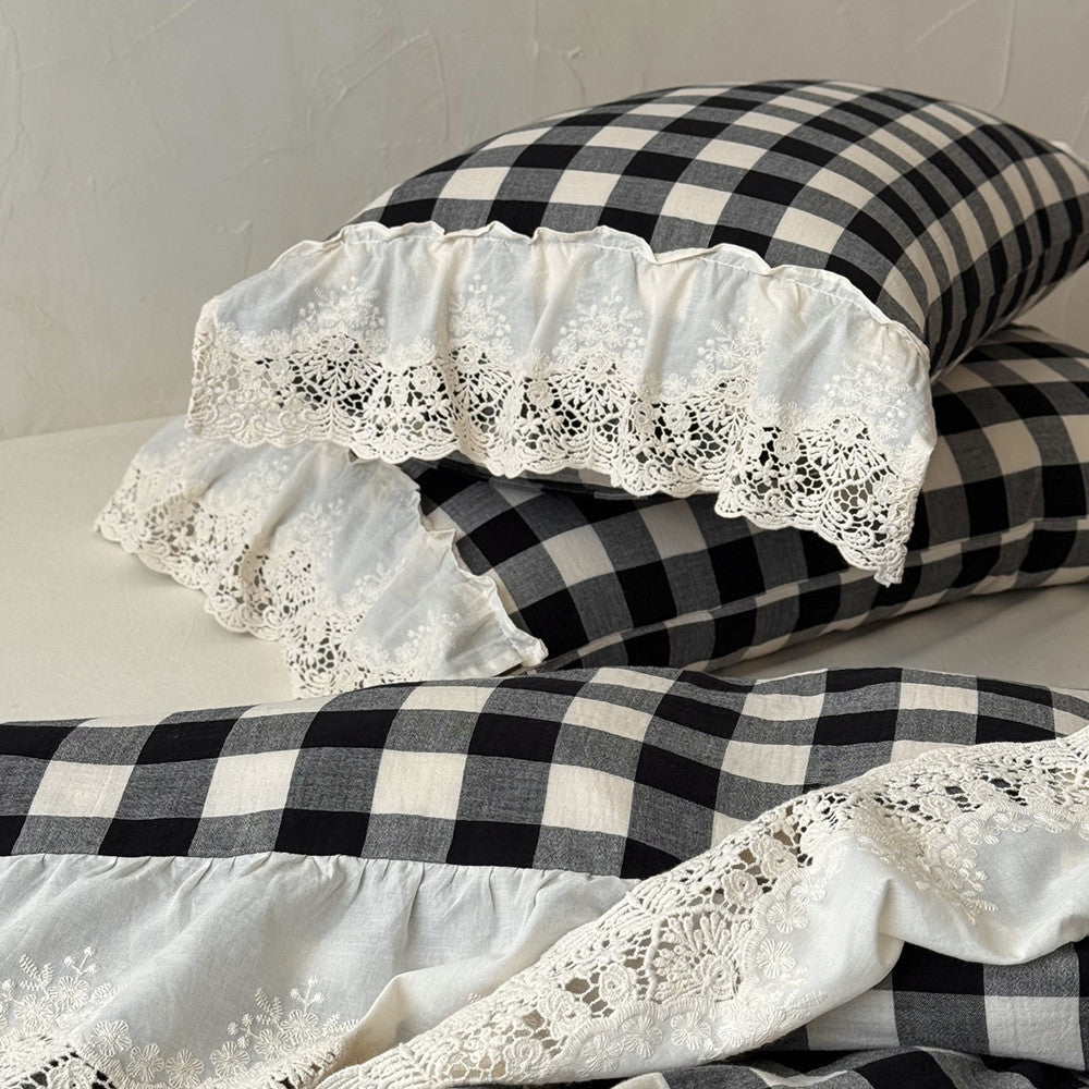 Black and white checkered pillows with lace trim on a neutral background