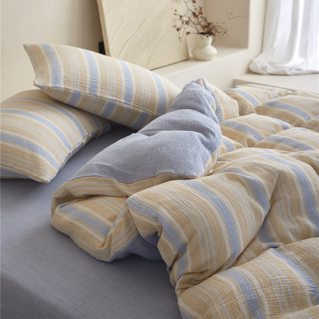 Detail of the Yellow & Blue duvet cover fold, showing the stripe pattern, soft gauze texture, and the solid blue sheet which matches the reverse side.