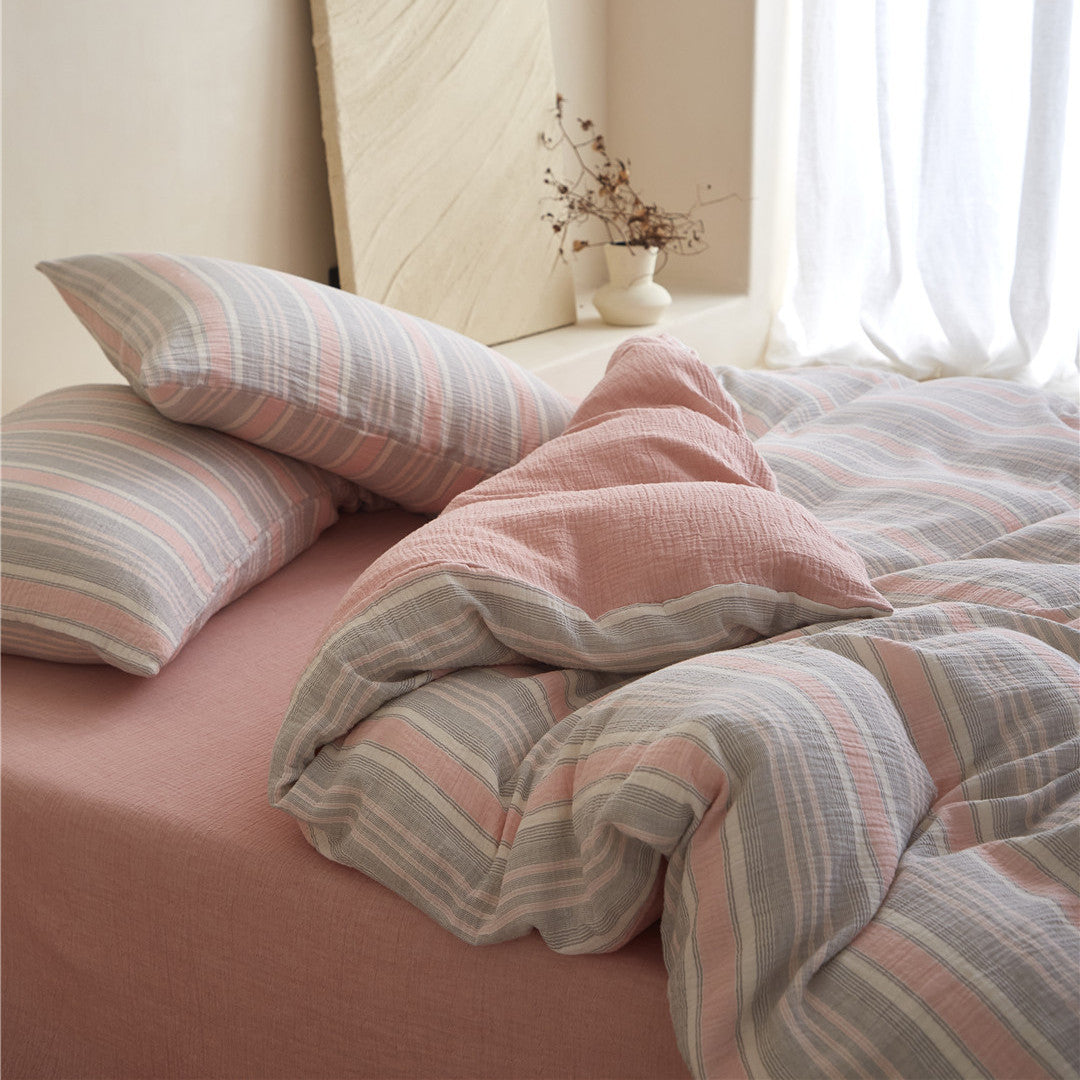 Close-up on the pillows and folded Grey & Pale Pink duvet cover, highlighting the reversible solid pink cotton gauze layer.