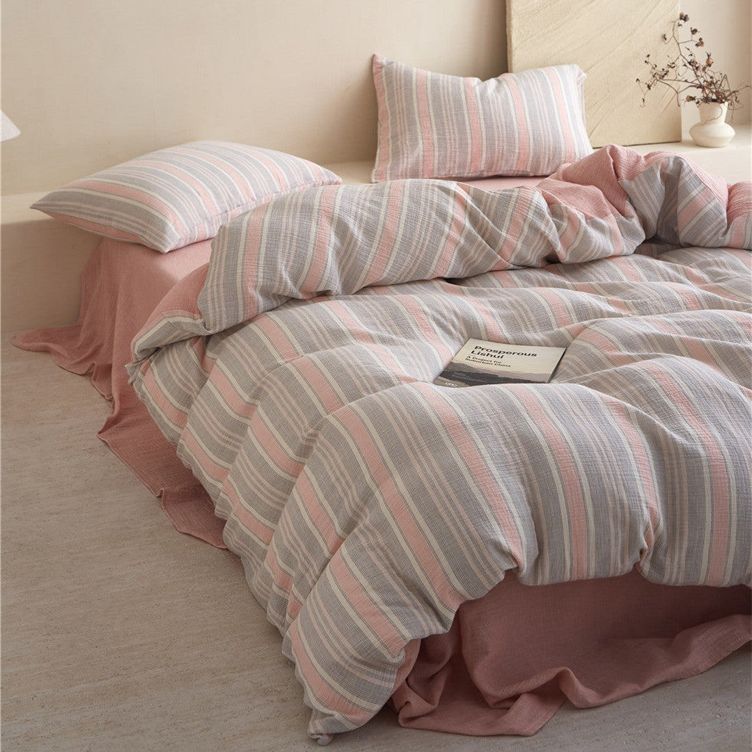 Styled low-angle shot of the Grey & Pale Pink Striped Bedding Set, featuring the pink sheet and the soft, rumpled look.