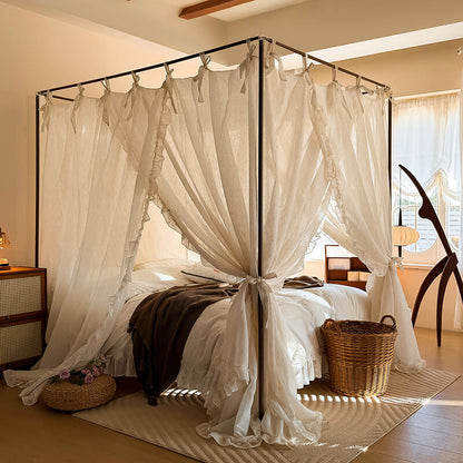 Four-poster bed with white curtains in a bedroom setting