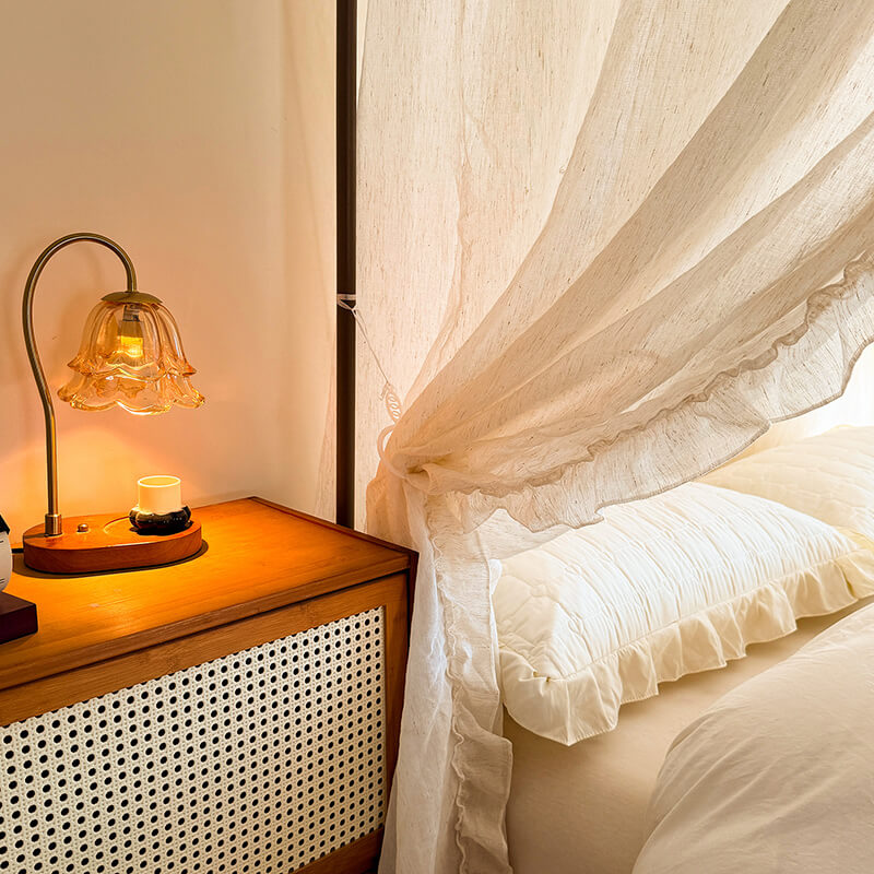 Bedroom scene with a nightstand and lamp next to a bed with white bedding.