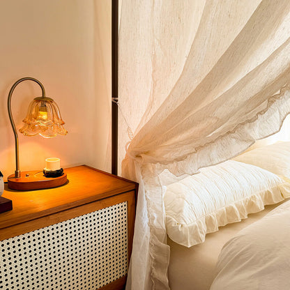 Bedroom scene with a nightstand and lamp next to a bed with white bedding.
