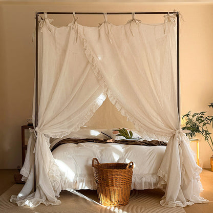 Four-poster bed with white curtains and a wicker basket on a wooden floor.