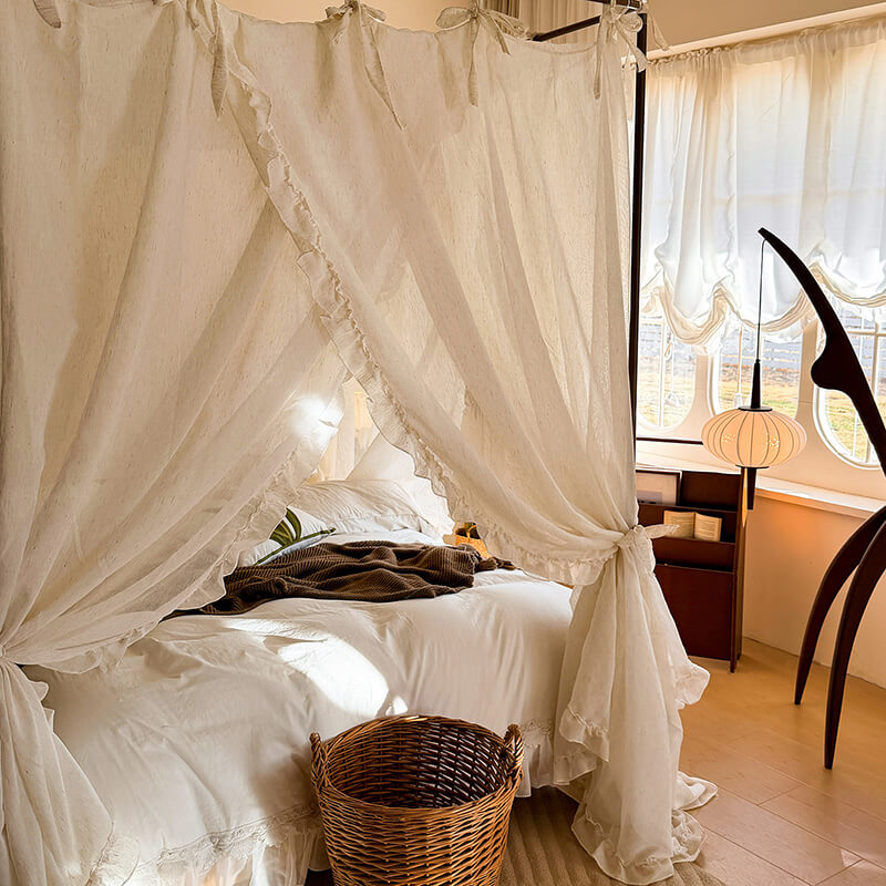 Bedroom with a canopy bed draped in white curtains, a basket on the floor, and a lamp in the corner.