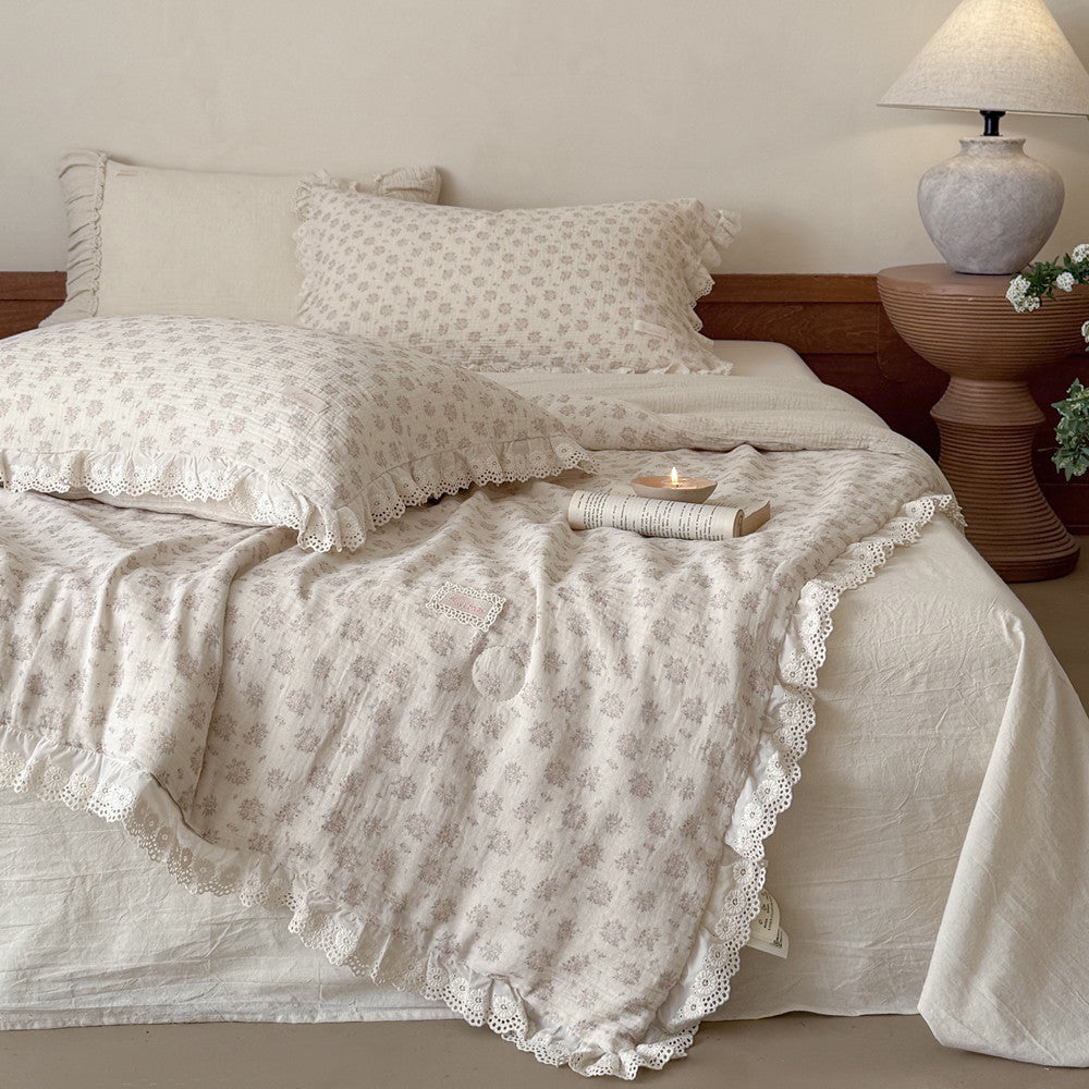 Cozy cottagecore bedroom setting showcasing a fluffy dusty pink floral comforter with elegant white eyelet lace ruffle edges on a styled bed.