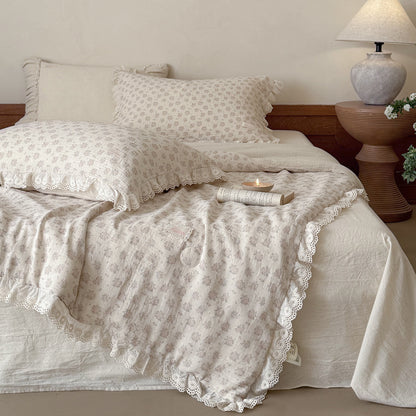 Cozy cottagecore bedroom setting showcasing a fluffy dusty pink floral comforter with elegant white eyelet lace ruffle edges on a styled bed.