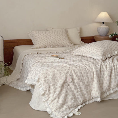 Detailed look at a vintage floral quilted comforter made of cotton linen blend, highlighting the delicate rose bud prints and crinkle fabric.