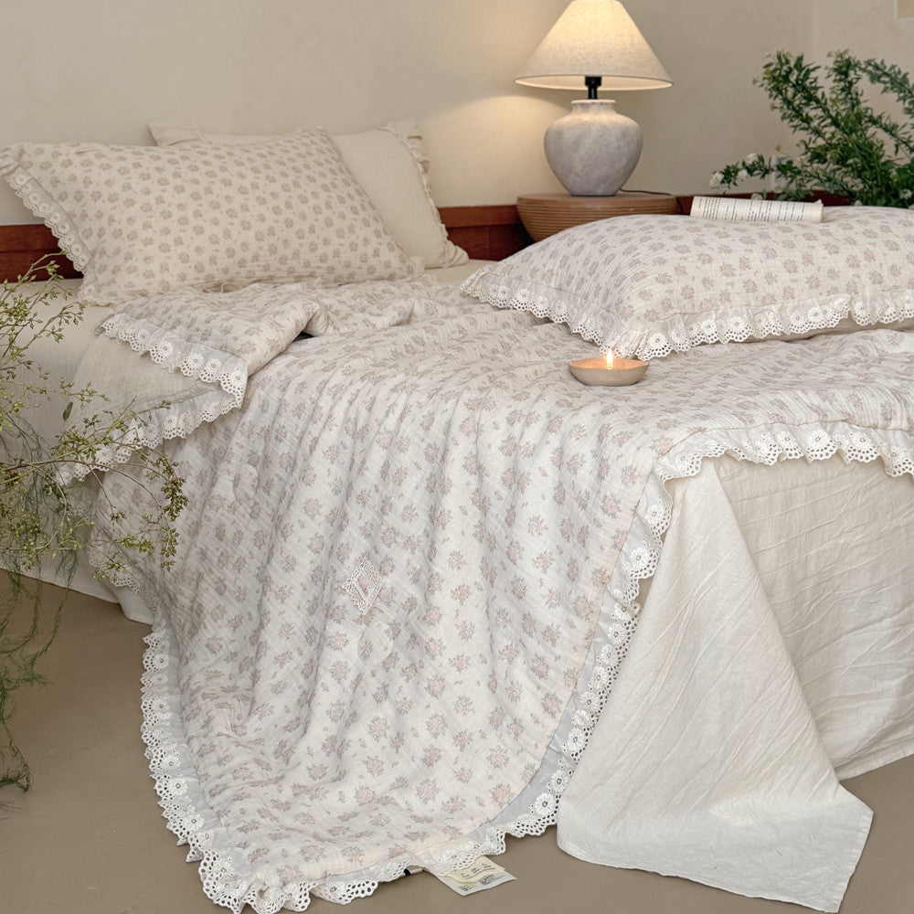Close-up shot of the exquisite embroidered hollow-out lace trim on a dusty pink shabby chic floral comforter.