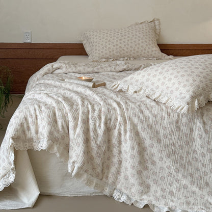 Aesthetic layered bedding display with a thick pink floral comforter and matching ruffled pillowcases under warm bedroom light.