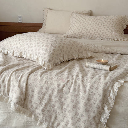 Texture-focused shot of a quilted cotton-linen comforter featuring romantic French cottage pink botanical motifs and delicate stitching.