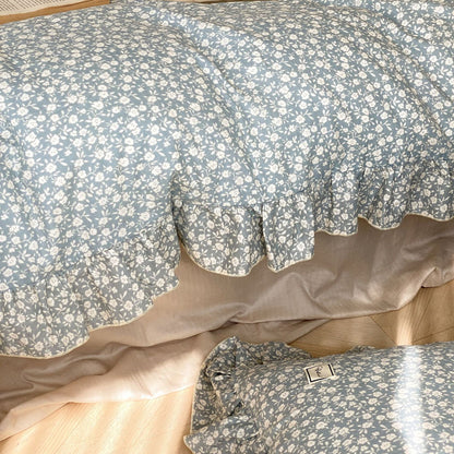 Detailed image of the blue ditsy floral bedding duvet edge, clearly showing the scalloped ruffled edges and the cotton muslin texture.
