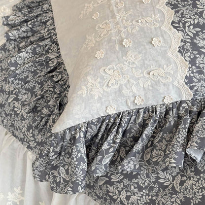 Close-up of embroidered ivory pillow panel with gray botanical ruffle trim