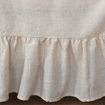 A detailed view of the bottom hem of the beige sofa cover, showcasing the delicate ruffles and the linen-like texture of the fabric.