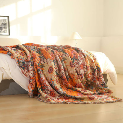 Warm orange daisy floral cotton throw blanket draped over a bed