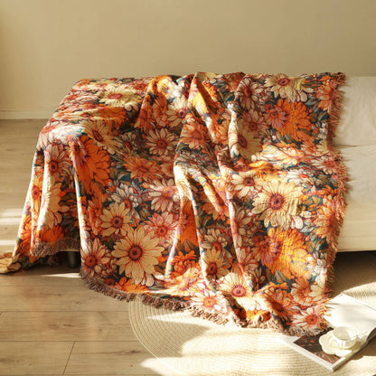 Daisy floral cotton throw blanket with fringe draped over a sofa