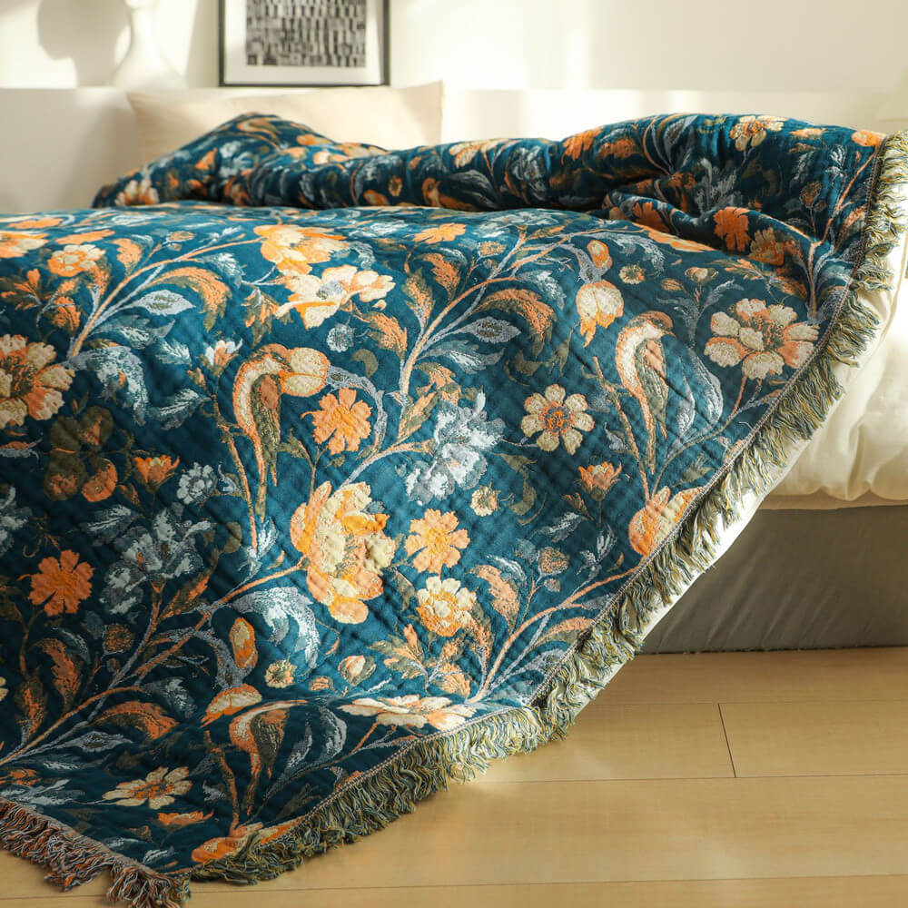 Close view of dark teal floral cotton throw blanket with fringe on a bed
