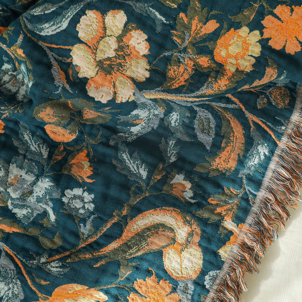 Jacquard-woven botanical cotton throw blanket showing floral bird details and fringe edge