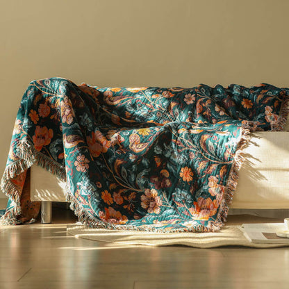 Dark teal botanical cotton throw blanket draped over a cream sofa
