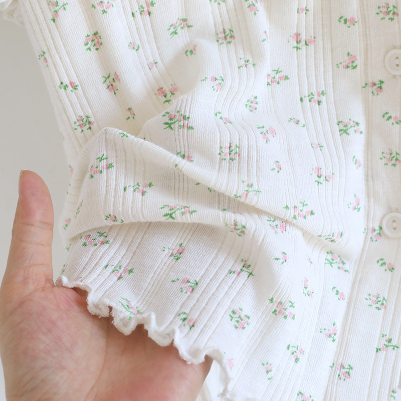 Close-up of white cotton pajama sleeve with ditsy floral print and scalloped edge