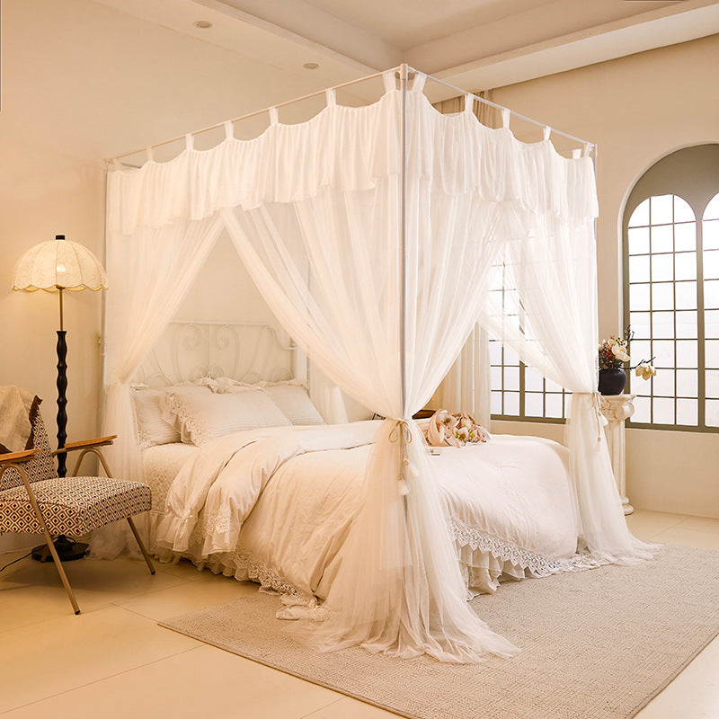 Elegant canopy bed with white cotton curtains and bedding in a cozy, sunlit bedroom.