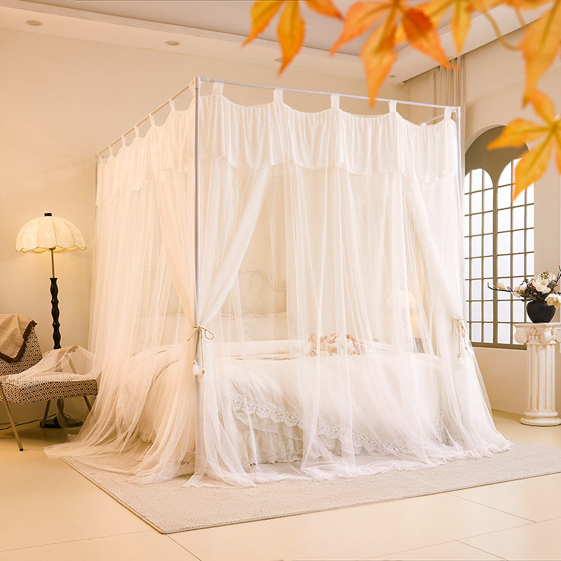 Elegant white canopy bed with sheer curtains in a cozy, naturally lit bedroom decor
